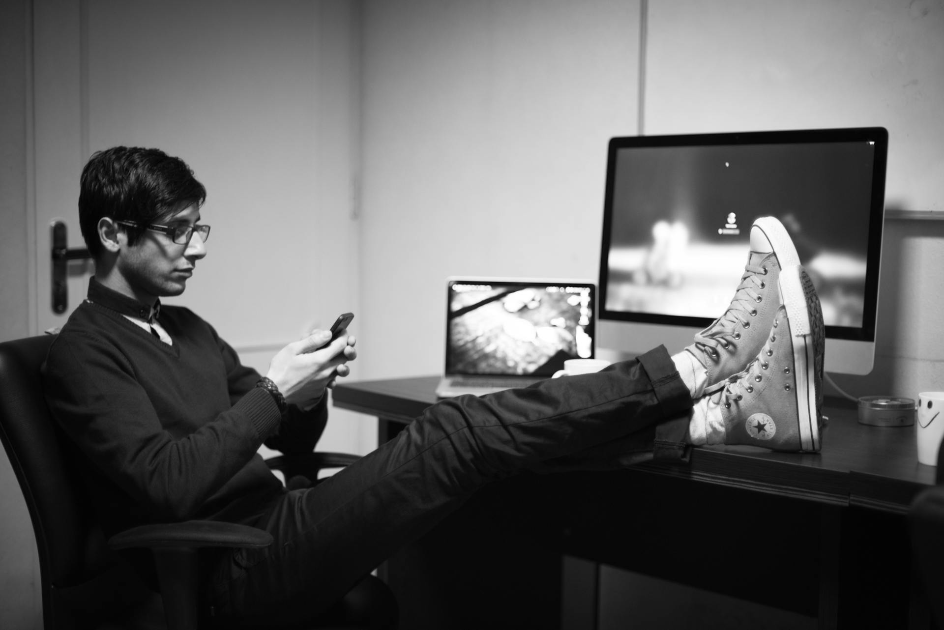 Persona teletrabajando con los pies apoyados sobre el escritorio en una oficina en casa