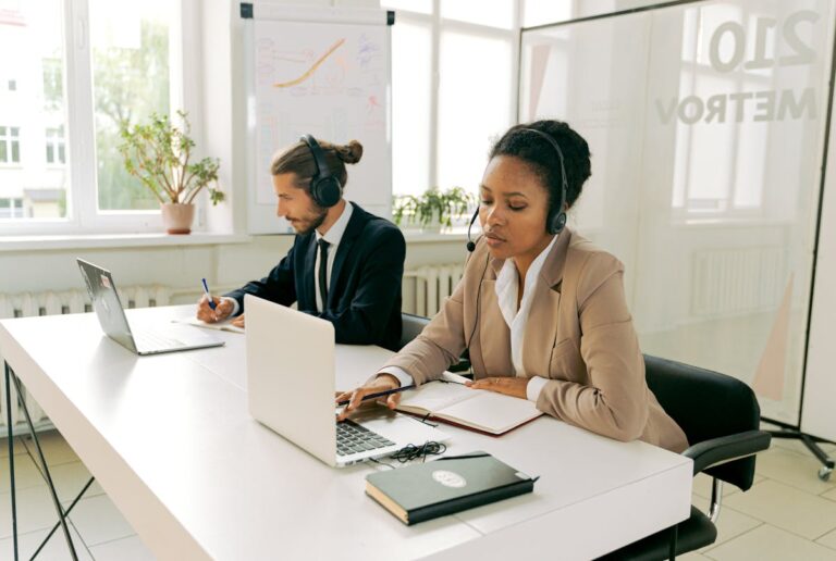 Persona con auriculares con micrófono trabajando en el portátil en una videollamada de teletrabajo