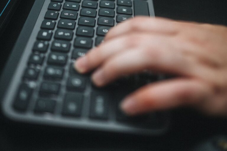 Manos escribiendo en un teclado inalambrico sobre un escritorio de teletrabajo